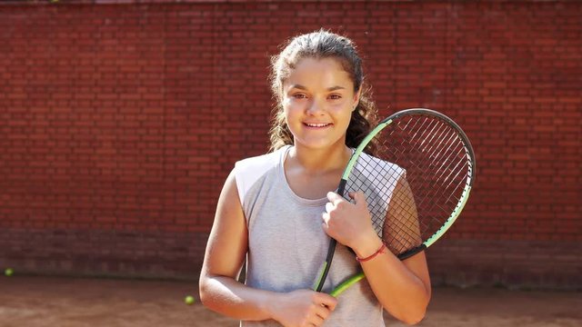 Portrait of pretty young tennis playgirl with racket smiling and going at camera
