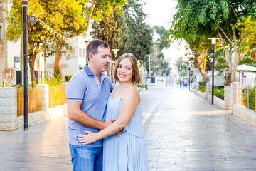 Obraz premium Portrait of adult happy hugging pregnant family, couple posing during walk in the city park. Fertility concept. Sunset light. soft selective focus, Copy space.