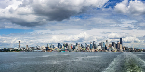 Obraz premium Seattle skyline seen from a Washington State ferry boat on the Puget Sound on a cloudy sunny day, WA, USA.