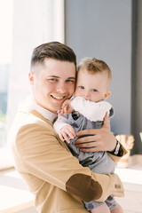 A handsome young dad hugs his one-year-old son. Cute baby. Happy family