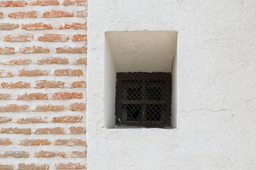 Un pequeño ventanuco con 2 texturas de pared diferentes dispuestas en los tercios de la fotografía
