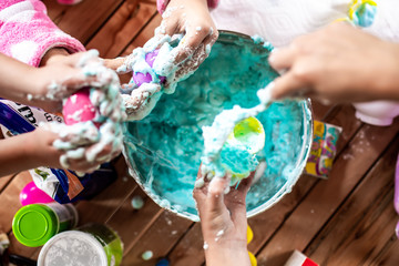 A group of young girls, children make a mess with frothy slime at a birthday party