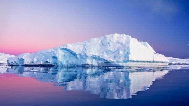 Antarctic Nature. Huge long iceberg with mirror reflection floats in open ocean. Sunset sky in the background. Majestic winter landscape. Explore beauty world, holidays. 4K Slow motion Parallax Effect