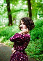 Wonderful  girl with curly hair poses in the park