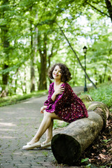 Pretty girl with curly hair poses in the park