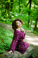 Fototapeta na wymiar A good girl with curly hair poses in the park
