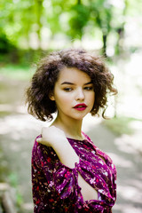 Naklejka premium Delicate girl with curly hair poses in the park