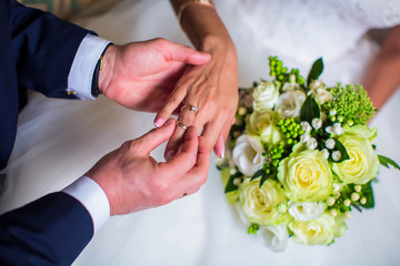 Groom putting gold wedding ring on bride's finger, closeup