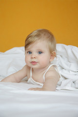 Portrait of adorable blonde baby in the bed