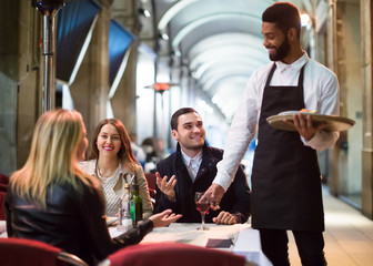 Afro waiter taking table order and smiling