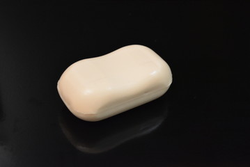 On a black glossy background, a fragrant body soap with reflection