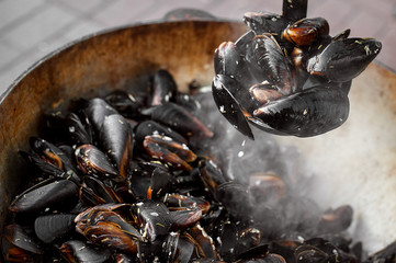The process of preparing mussels in a large saucepan. Street food with seafood.