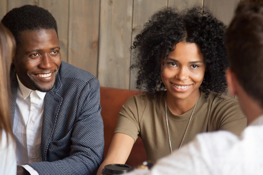 Smiling Black People Listening To Colleague Talking Having Coffee At Work Break, African American Couple Spending Time Together With Diverse Friends, Enjoying Drinks In Cafe, Workers Chilling Out