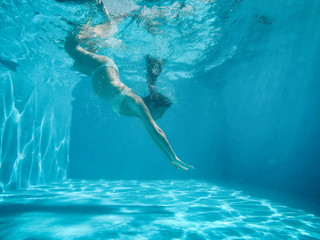 Pregnant woman under the water of a pool