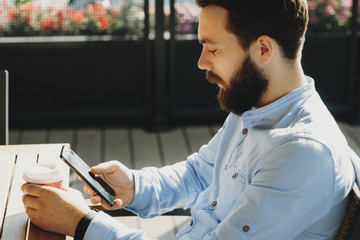 Man using smartphone sitting with coffee