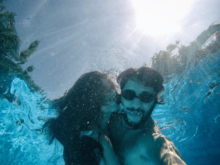 happy couple under the water in a pool
