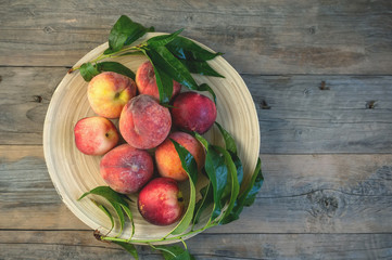 Fresh juicy peaches with leaves on dark wooden rustic background.