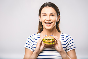 Young happy beautiful woman eating hamburger woman eating junk food, fatty food hamburger. White...