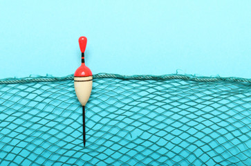 Fishing net with homemade bobber on blue background. Picture with space for your text. © Kletr