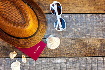 Flat Lay with hat, passport, sunglasses and shell on rustic trendy old vintage wooden background. Vacation travel summer weekend sea adventure trip concept