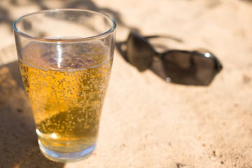 a glass of Cold beer and a sunglasses on the beach sand
