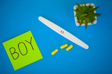 Pregnancy planning concep. Pregnancy test positive with two stripes and contraceptive pill on blue...
