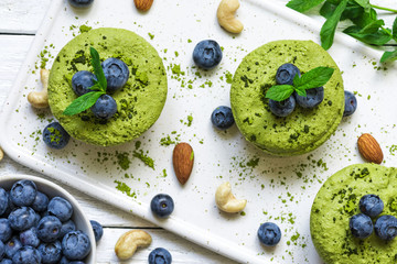 homemade raw matcha powder cakes with fresh berries, mint, nuts. healthy vegan food concept