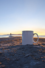 A solo blank white coffee mug and a solo man out on the sand bar of the great salt lake. 