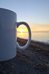 Colorful great salt lake sunset through the handle of a blank white coffee mug on the shoreline