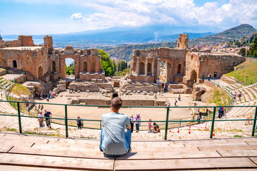 July 04, 2018. Taormina, Italy. Young man sitting at the caldron of the ancient Greek Theater of...