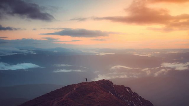 Man stand on top of mountain in sunrise soft light. Majestic nature landscape. Morning fog and clouds floats. Lifestyle, holidays, travel and recreation. Vintage toning. Slow motion 4K Time Lapse