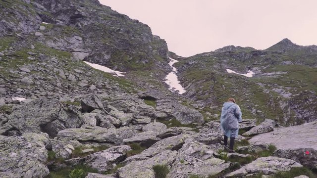 A young woman hiker climbs mountains and photographs landscapes on camera. Transfagarasan, Carpathian mountains in Romania