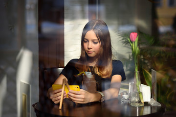 girl drinks coffee and watches video on mobile phone