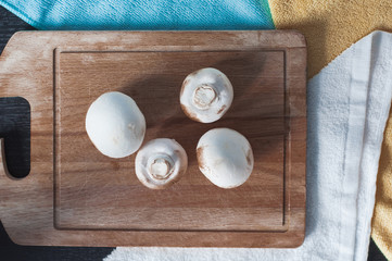 White mushrooms on the wooden board. Champignon on the desk before cooking