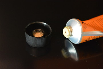 On a black  glossy background, caps and a tube of cream with reflection