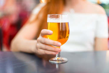 Young redhead pretty girl enjoying a beer at a mall