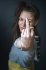 Defiant young woman giving you the middle finger, studio image, black background