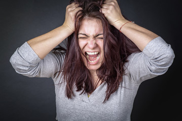 Frustrated angry woman screaming and pulling her hair, young woman angry