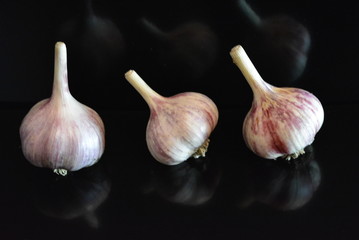 Fresh vegetables, three heads of a calf with a reflection on a black glossy surface with repeated reflection.