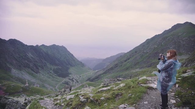 A young woman hiker climbs mountains and photographs landscapes on camera. Transfagarasan, Carpathian mountains in Romania