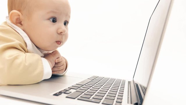 Focused baby girl works on a laptop