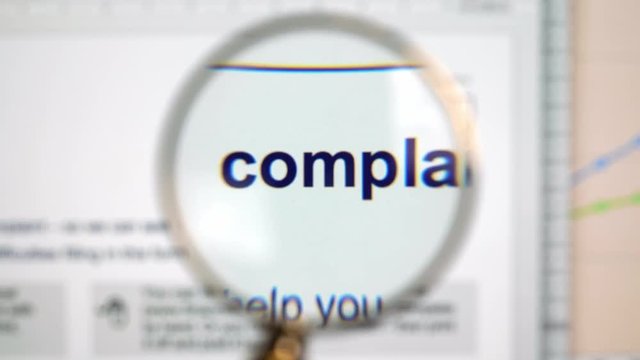 Complaint form being looked through a magnifying glass moving left to right. Locked down real time medium shot