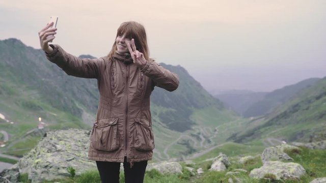 A young woman hiker climbs mountains and does selfie on smartphone camera. Transfagarasan, Carpathian mountains in Romania
