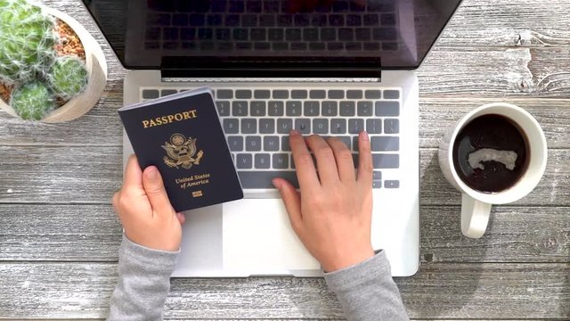 Person with an American passport typing information into a laptop