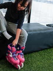 girl putting on inline roller skate shoes