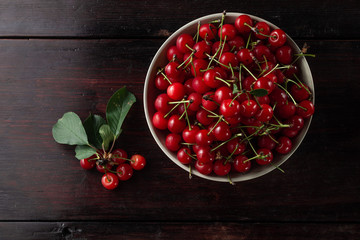 Fresh cherry on plate with summer flowers on rustic wooden background. fresh ripe berries. sweet cherries. top view