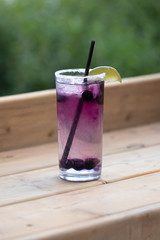 Fancy purple fruit drink with a lime on a patio