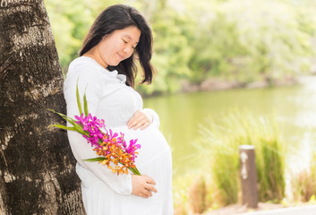 Naklejka premium Pregnant woman carry her belly and colorful flower with warm tone.