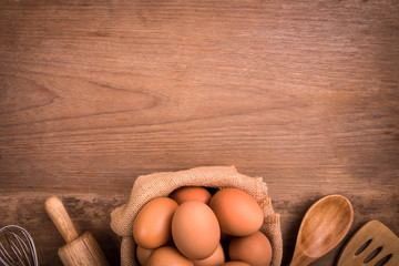 Fresh farm eggs on a wooden rustic background, Whipping eggs and whisk,top view with copy space