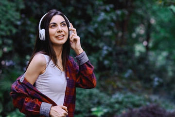 Young smiling woman listening to the music, through headphones on her head